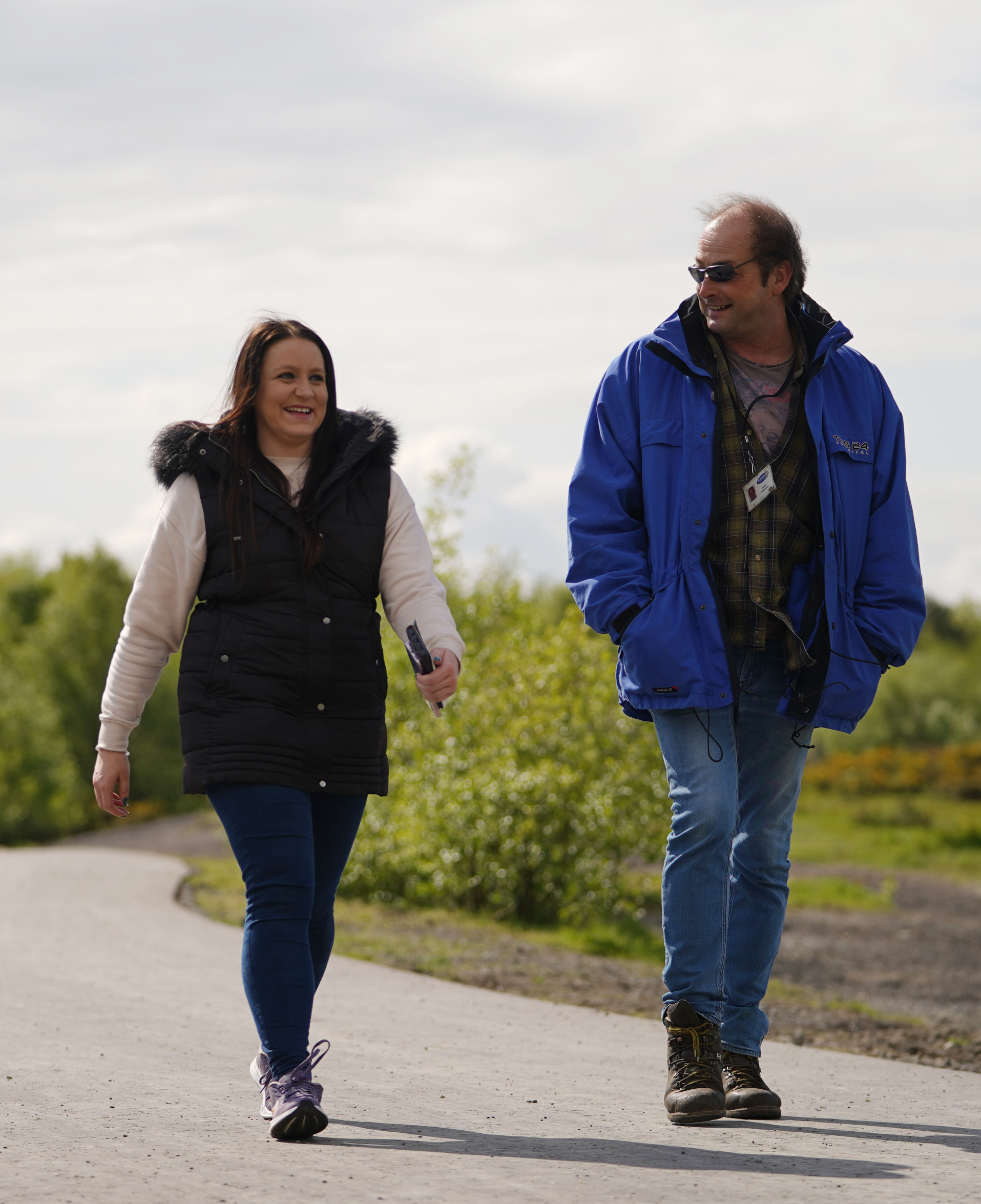 Lady in black Gilet and man in blue coat walking side by side along a path