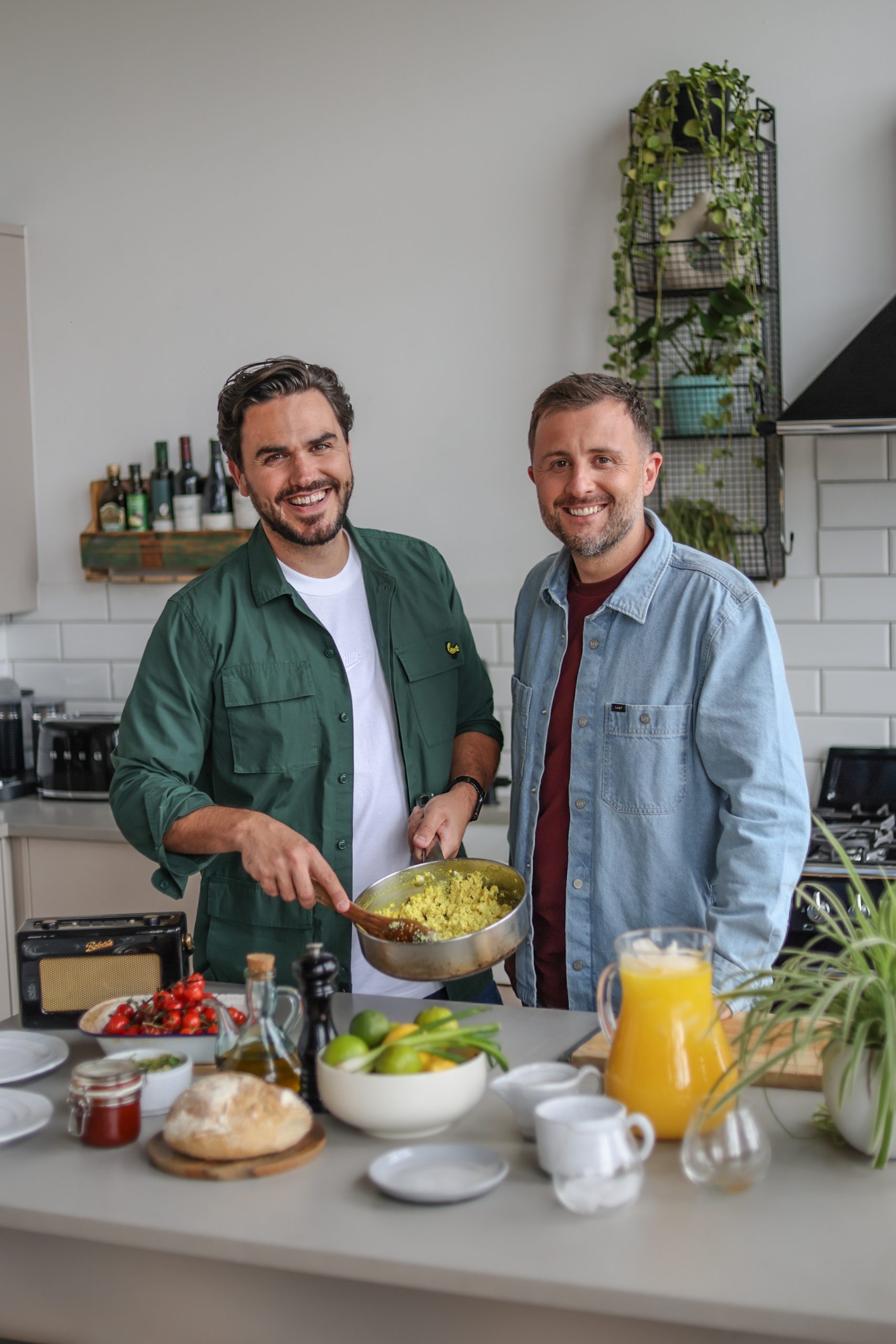 BOSH Chefs Henry Firth and Ian Theasby standing together in front of a kitchen bench covered in ingredients.