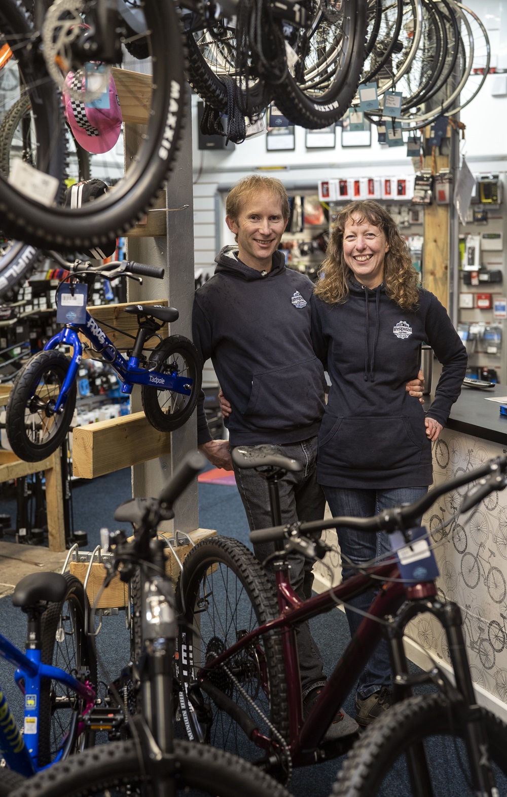 Gary and Fiona Ewing owners of Inspiral Cycles standing together surrounded by Bicycles