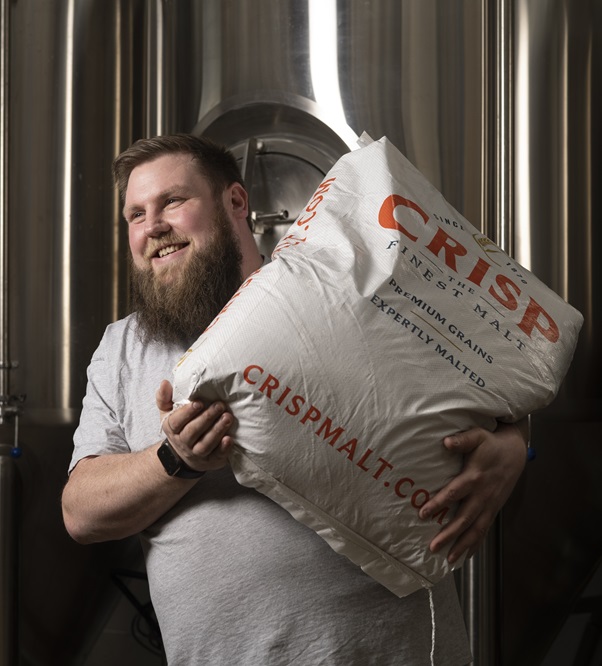 Ali Wild of Caps Off, standing with a bag of malt over his shoulder