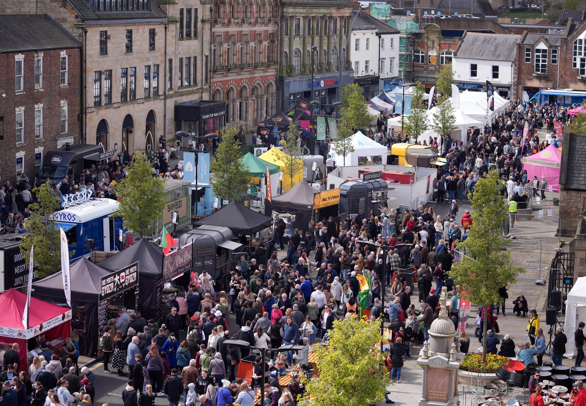 Aerial view of Bishop Auckland Food festival with colourful Gazebos lining the streets and crowds of people in the market place.