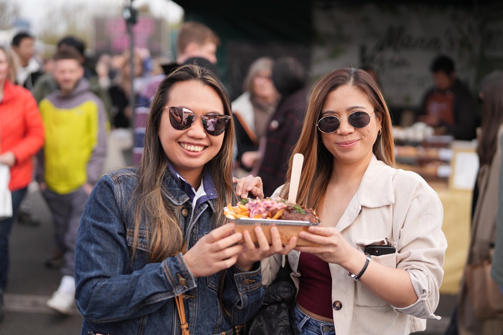 Two ladies wearing sunglasses holding a tray of food