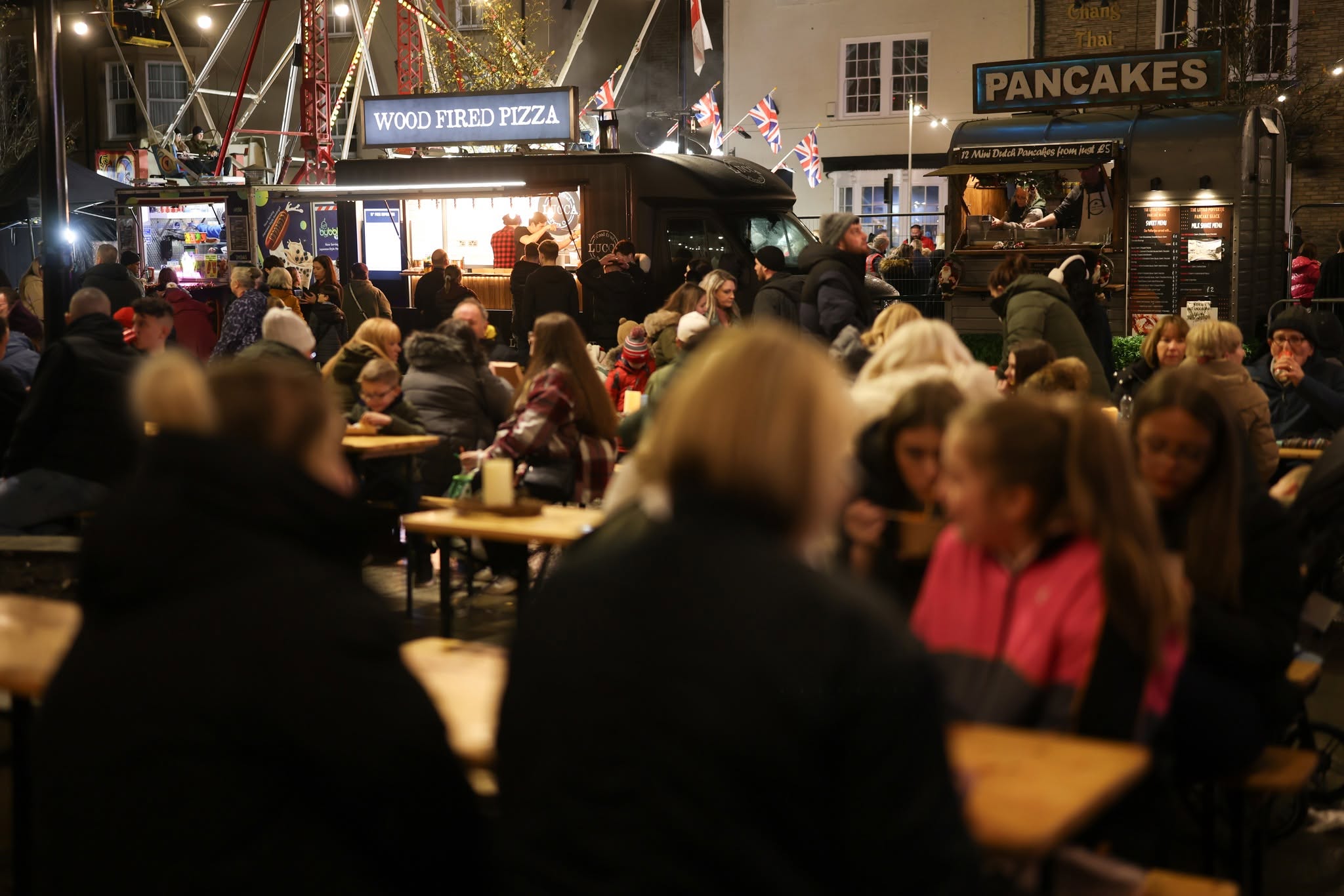 People sitting at tables in Bishop Auckland Market Place with a food stall in the background